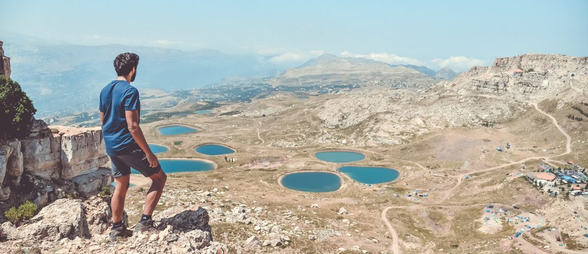 Man standing above valley in Lebanon with water reservoirs below