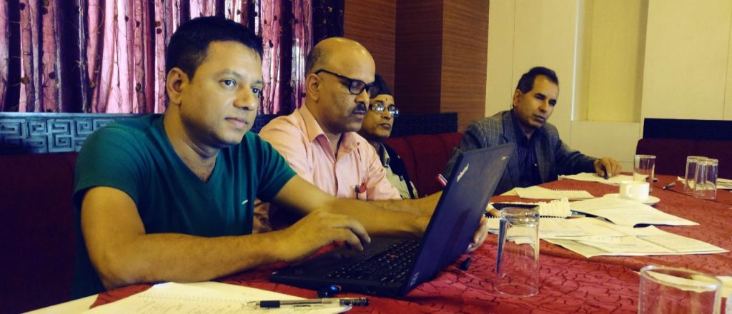 Four nepalese men at a table working on laptops