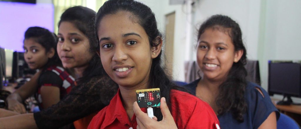 Girls in a classroom holding a circuit board