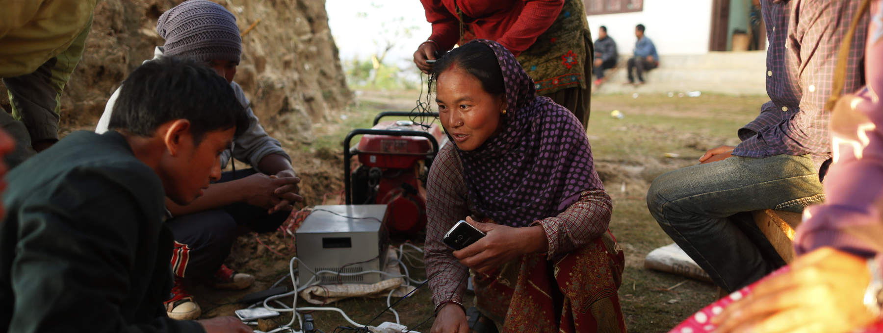 Young villagers giggle as they get the chance to charge their mobile phones from a generator in the destroyed village of Paslang near the epicenter of Saturday's massive earthquake in the Gorkha District of Nepal, Tuesday, April 28, 2015.  Military operations continue Tuesday to reach the isolated areas following the powerful earthquake that has devastated the nation and killed at least 4,400 people, according to district official Surya Mohan Adhikari. (AP Photo/Wally Santana)