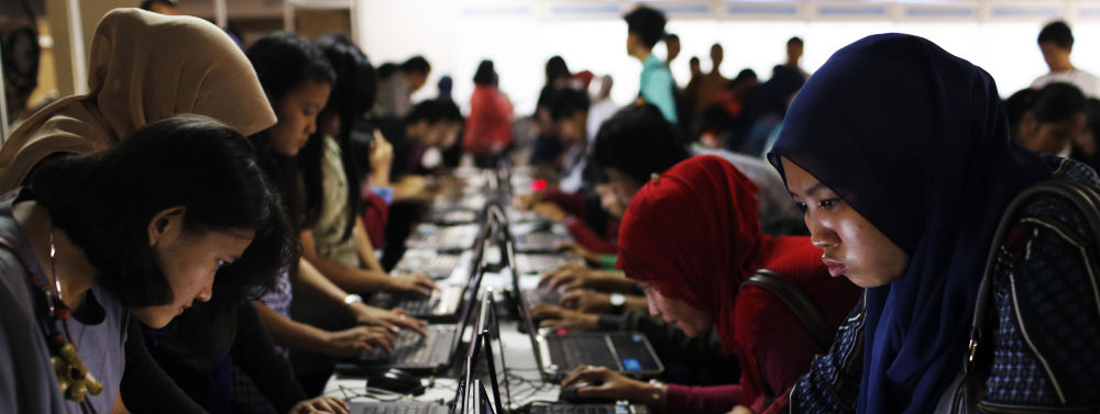 Indonesian youths fill out job application forms on laptops provided by the organizers at Kompas Karier Fair in Jakarta