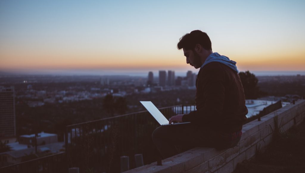 Man seated on bench with his laptop