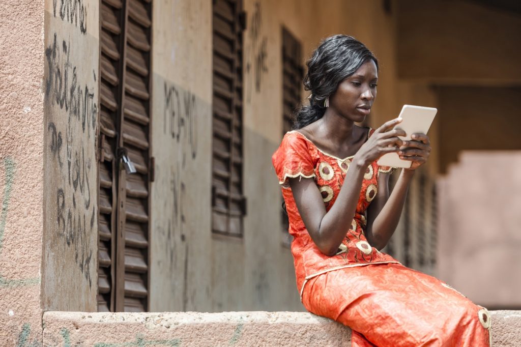 Young woman in orange dress uses a tablet computer