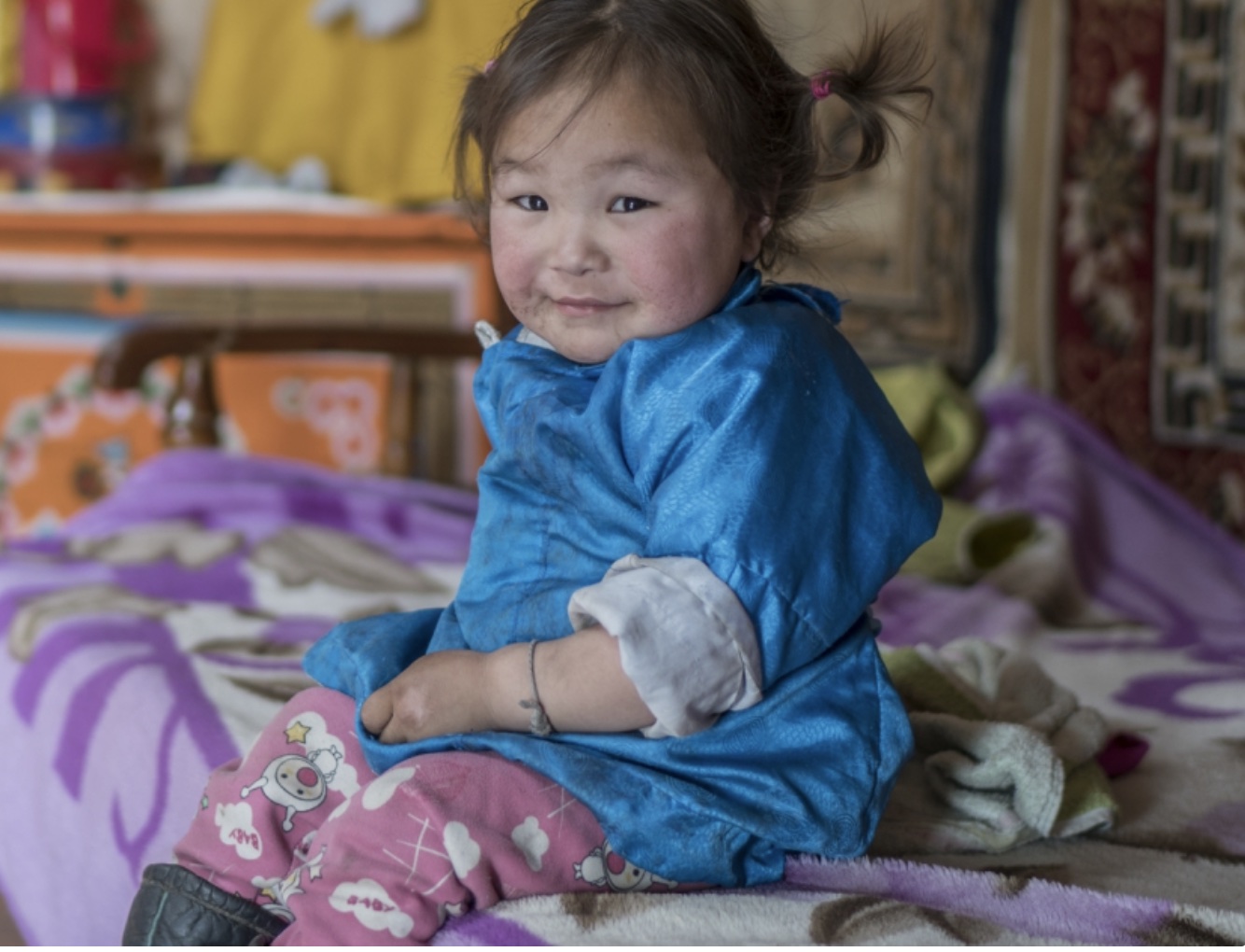 A small girl sitting on a bed