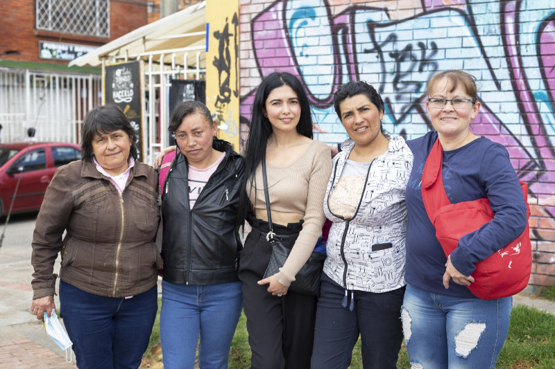 Five women standing in front of a graffiti-covered wall in Bogotá Colombia