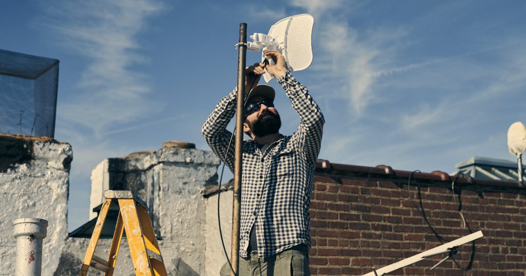 Chris Gregory instalando una antena Litebeam en una azotea