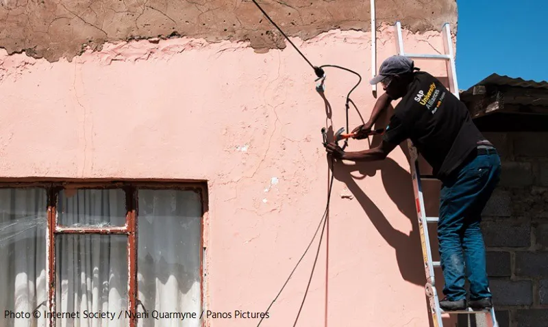A man fixing wires to the wall of a house