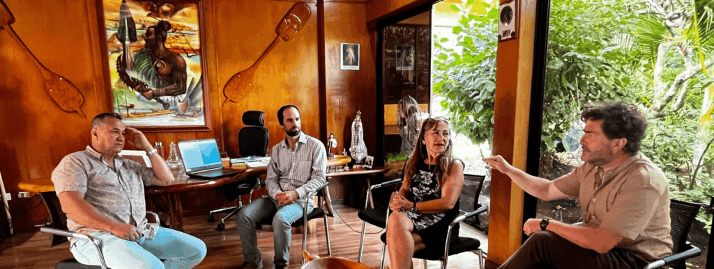 Several people gathered around a table, actively conversing in a spacious room with neutral decor.