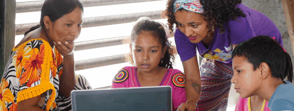 A woman and three children are interacting with a laptop.