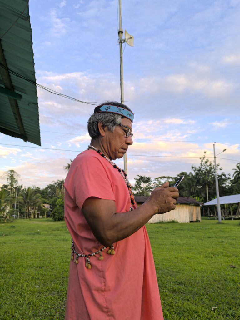 An Indigenous man is using the phone in an outdoor space.