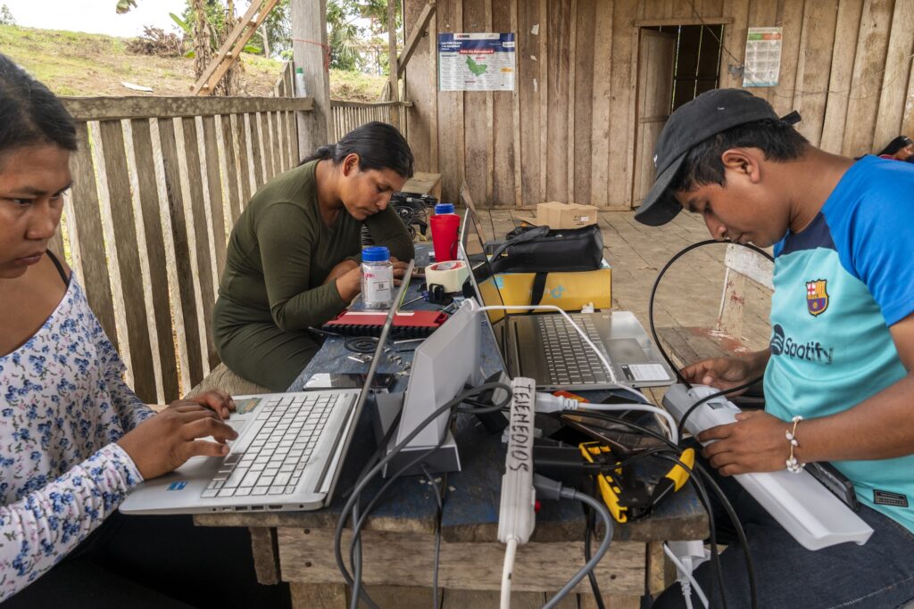 Indigenous peoples working together on laptops and Internet cables.