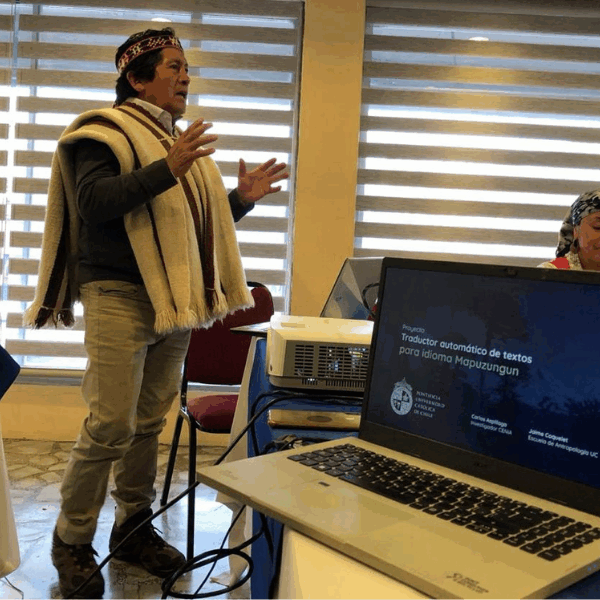 An indigenous man speaking in front of a laptop.