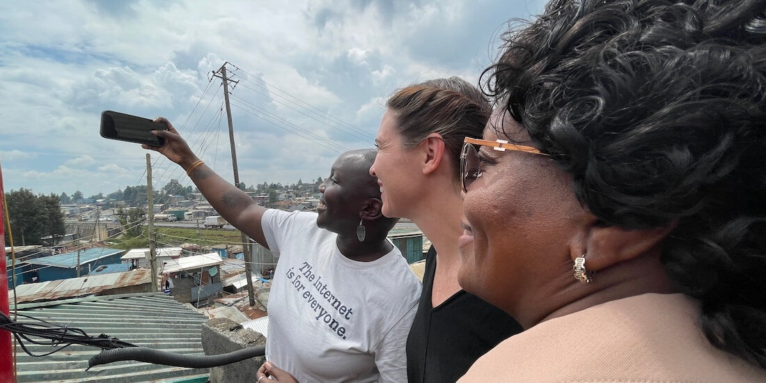 Three women smiling and posing together for a selfie with a cell phone