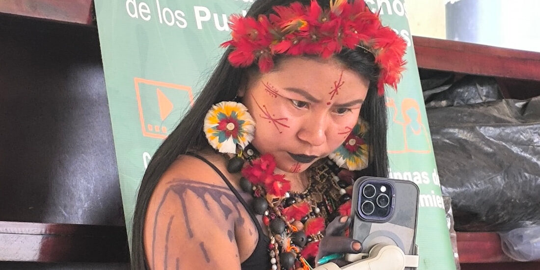 A woman with a colorful face painting holds a smartphone