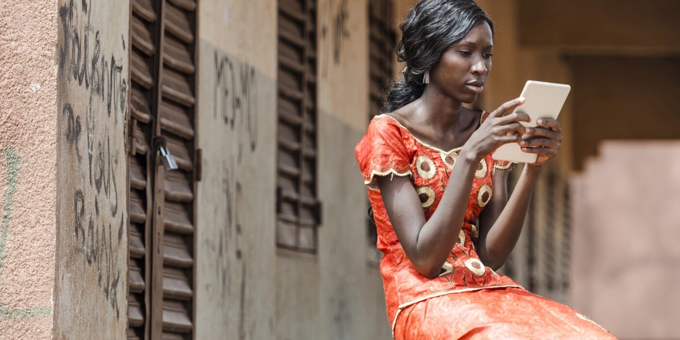Young woman in orange dress uses a tablet computer